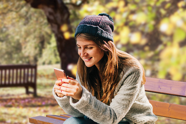 young woman sitting on a bench with a smartphone, wearing a toque